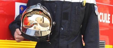 Photo du buste d'un pompier tenant son casque au niveau de son buste