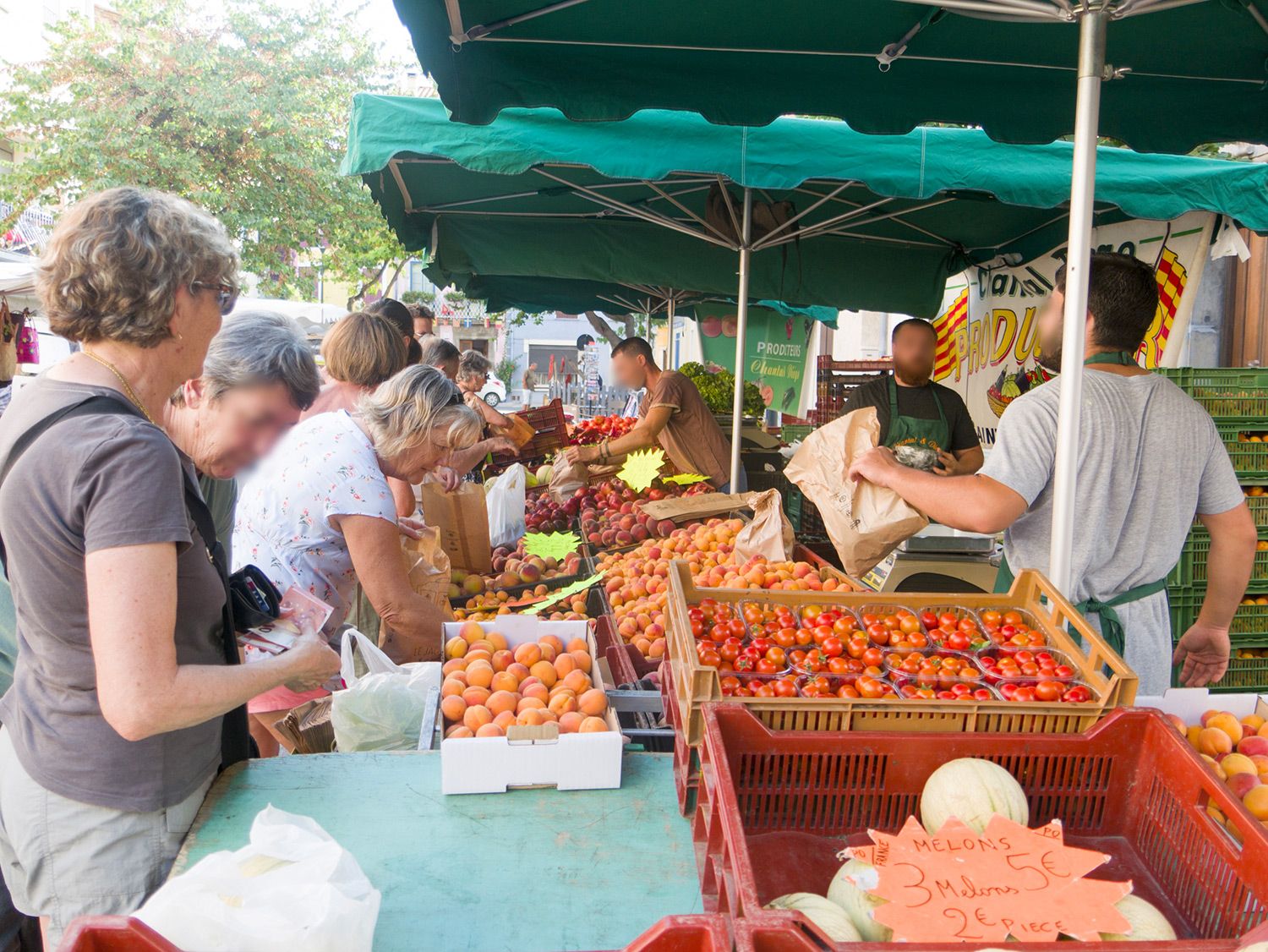 Photo d'un étale de fruit et légume au marché avec trois marchand et beaucoup de clients