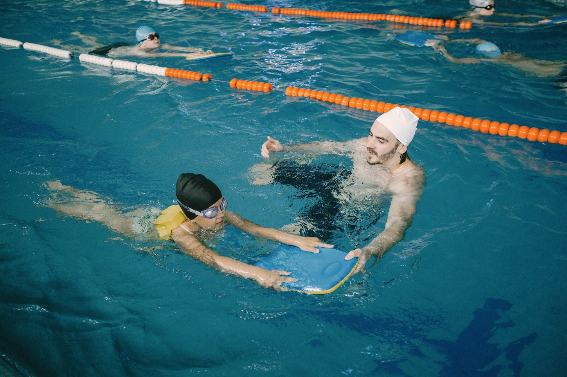 Un maître nageur apprend a un enfant a nager avec une planche.
